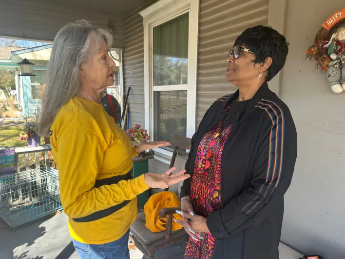 An ECDR volunteer listening to a resident on her porch