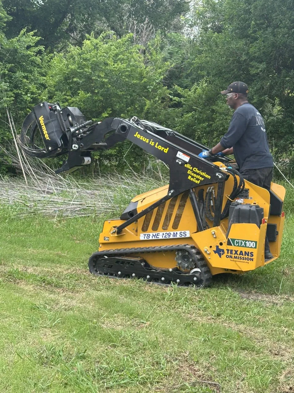 An ECDR volunteer clearing storm debris with a skid-steer