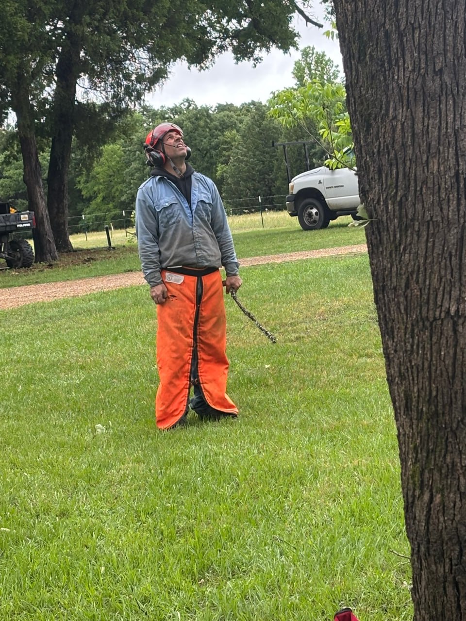 A chainsaw ministry volunteer wearing protective gear watches work near a tree during the Athens community service project.