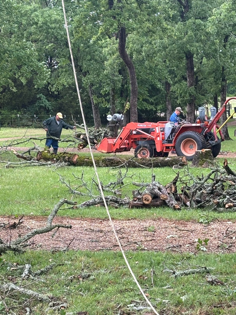 Chainsaw ministry volunteers use a tractor to clear cut branches during the Athens community service project.