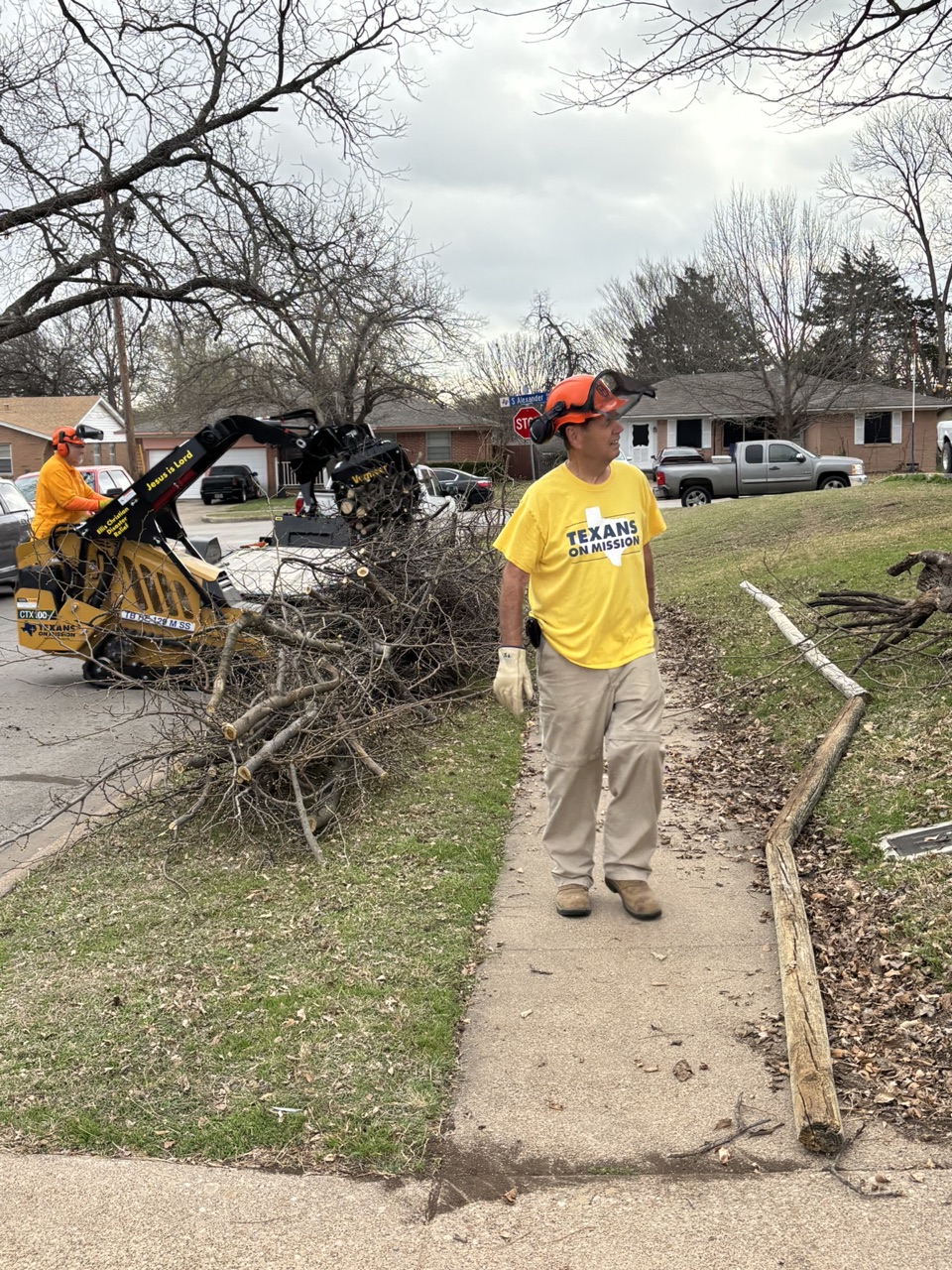 Chainsaw ministry volunteers clearing tree limbs with a mini skid steer during the Duncanville community service project.