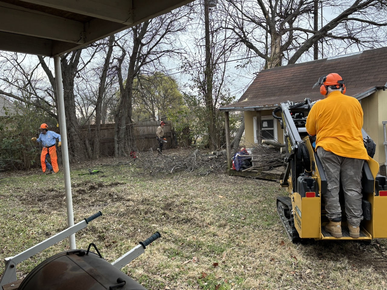 Volunteers using chainsaws and a mini skid steer to clear storm-damaged trees in Duncanville.