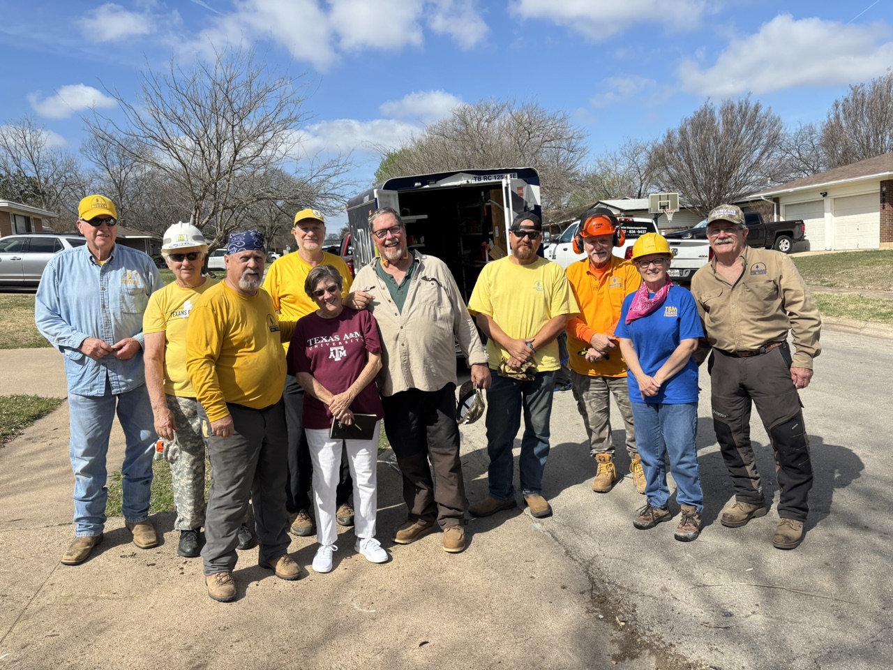 Volunteers hauling cut tree limbs with a mini skid steer during the Duncanville cleanup.