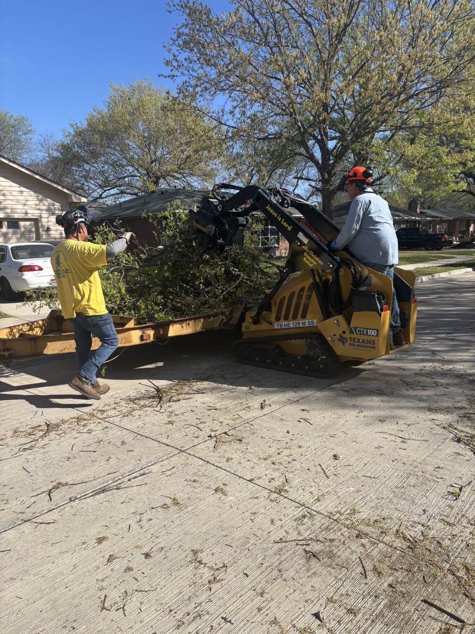 Chainsaw ministry volunteers load cut branches with a mini skid steer during the Waxahachie project.