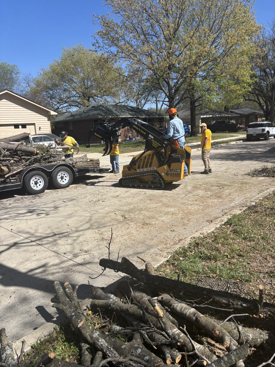 Chainsaw ministry volunteers use a mini skid steer to move cut branches onto a trailer in Waxahachie.