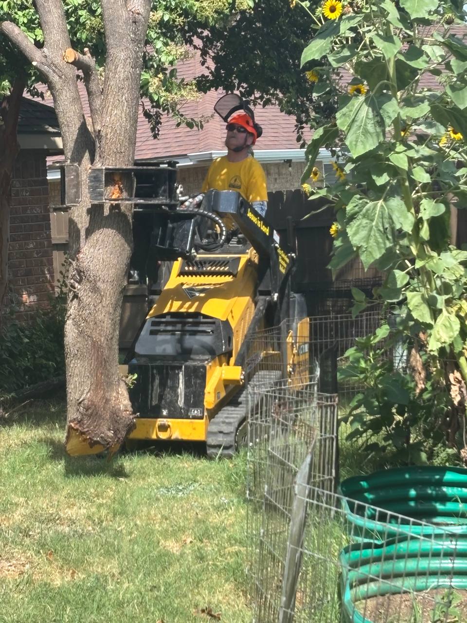 Chainsaw ministry volunteer using a mini skid steer to remove a cut tree trunk during the Roberts project.