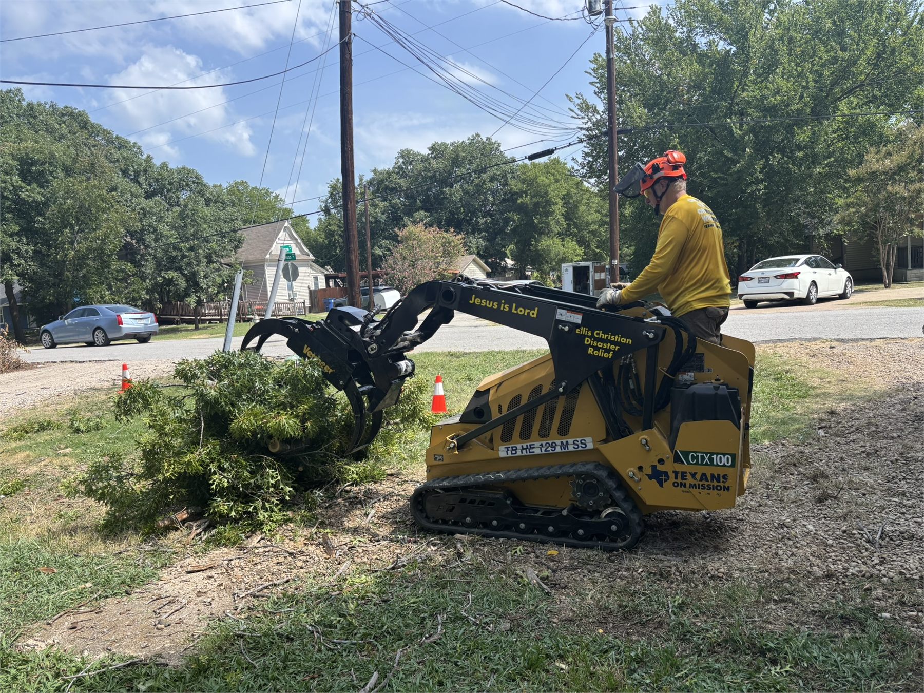 Volunteer moves cut branches with an ECDR mini skid steer during the Waxahachie community service project.