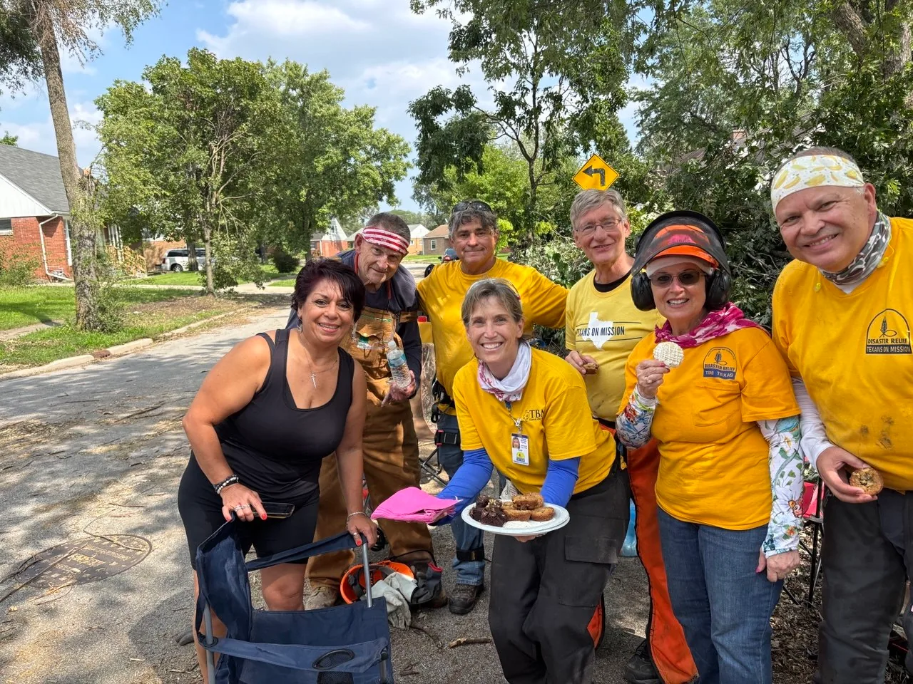 Glenwood homeowner standing outdoors with six ECDR and Texans On Mission chainsaw volunteers.