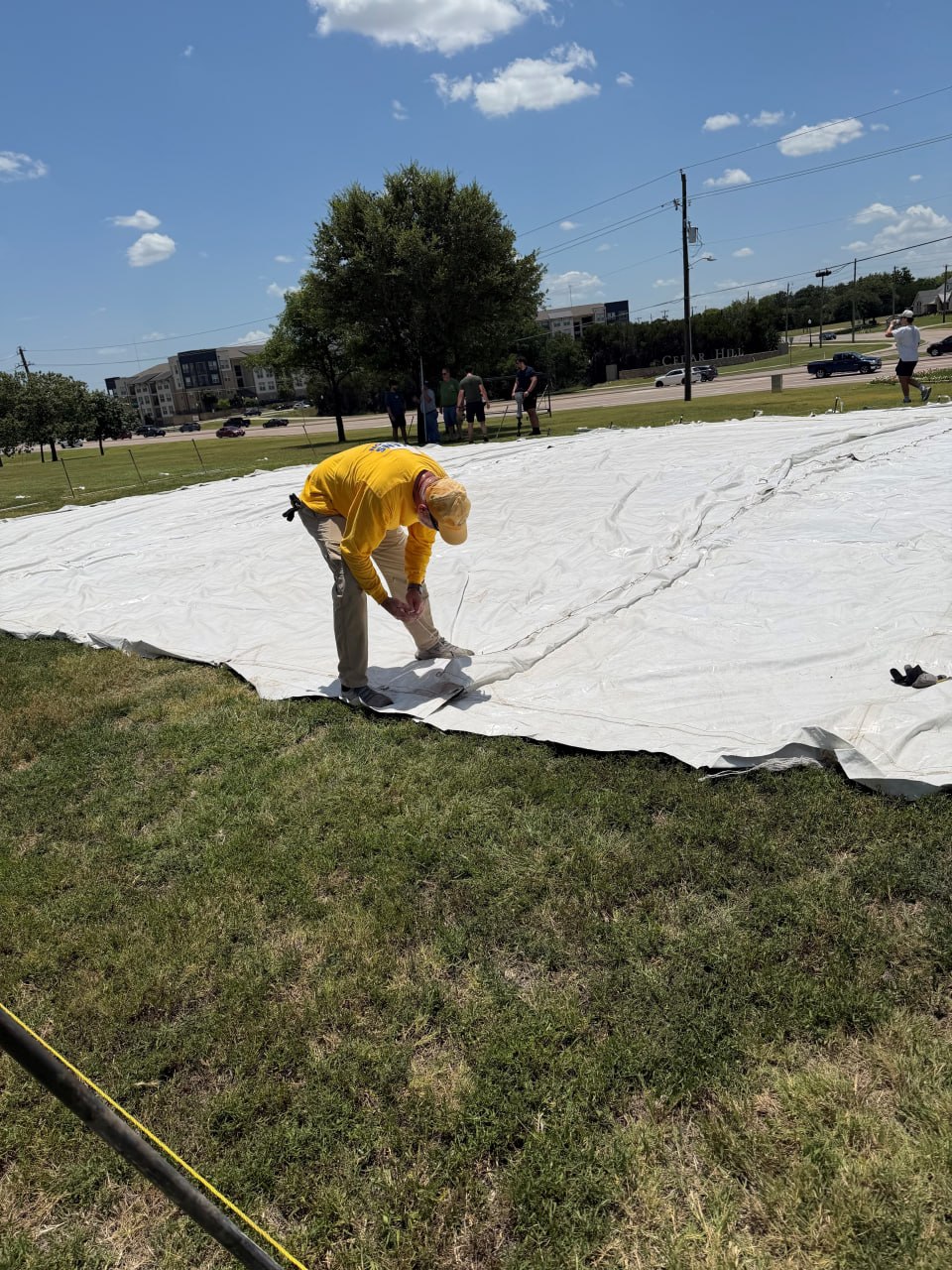 Volunteer staking down a large white tent cover on the lawn at Hillcrest Baptist Church.
