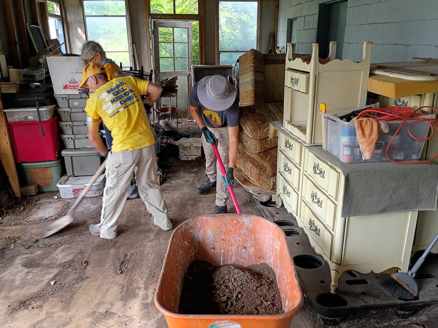Texans On Mission volunteers sweep flood debris from a Kerrville home during recovery work.