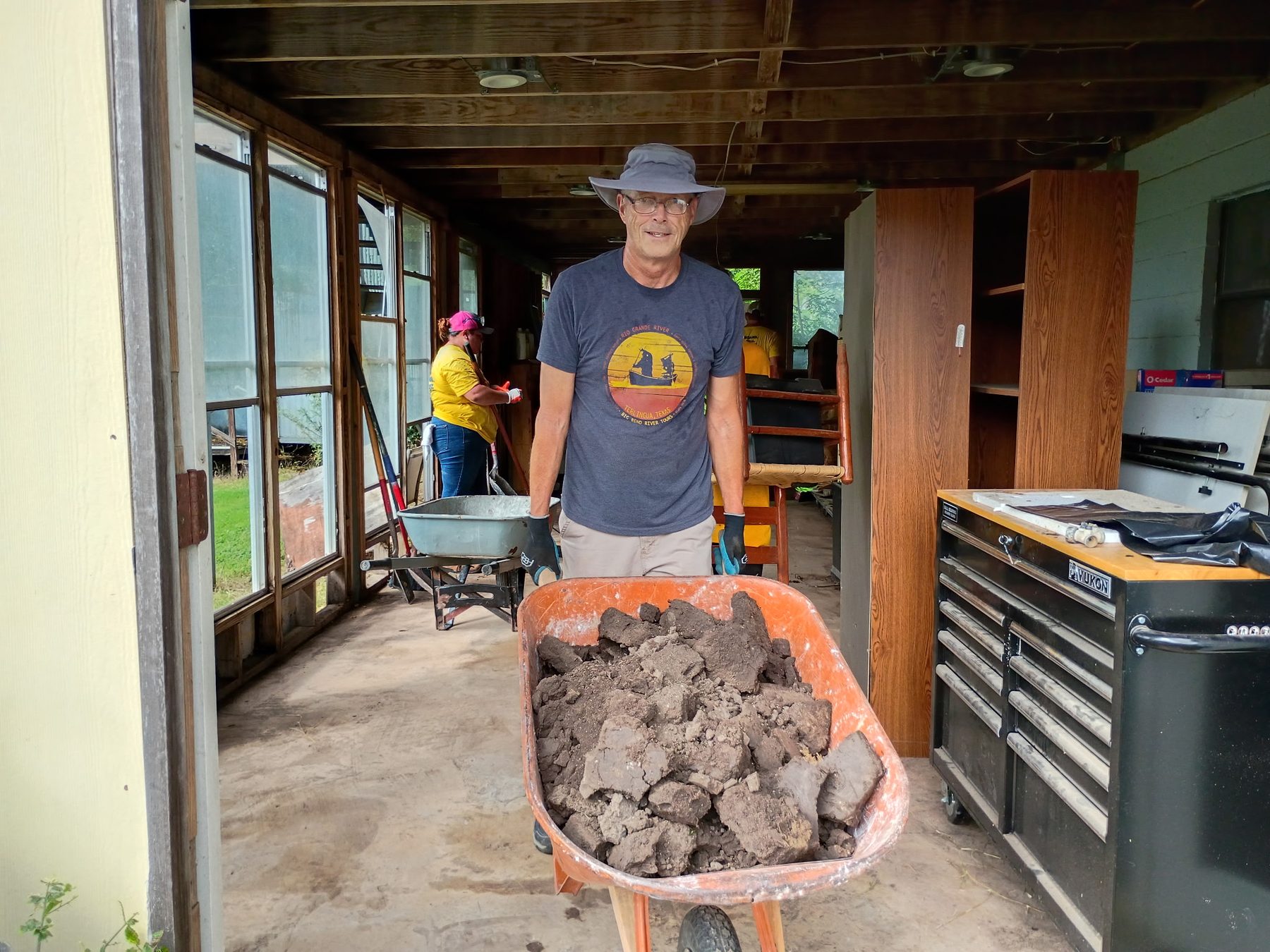 Volunteer moves a wheelbarrow filled with dried flood debris from a Kerrville home.