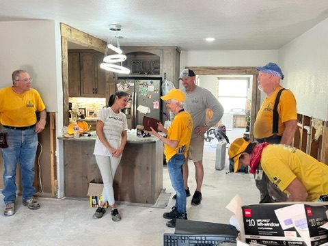 Texans On Mission volunteers visit with residents inside a Kerrville home during flood recovery.