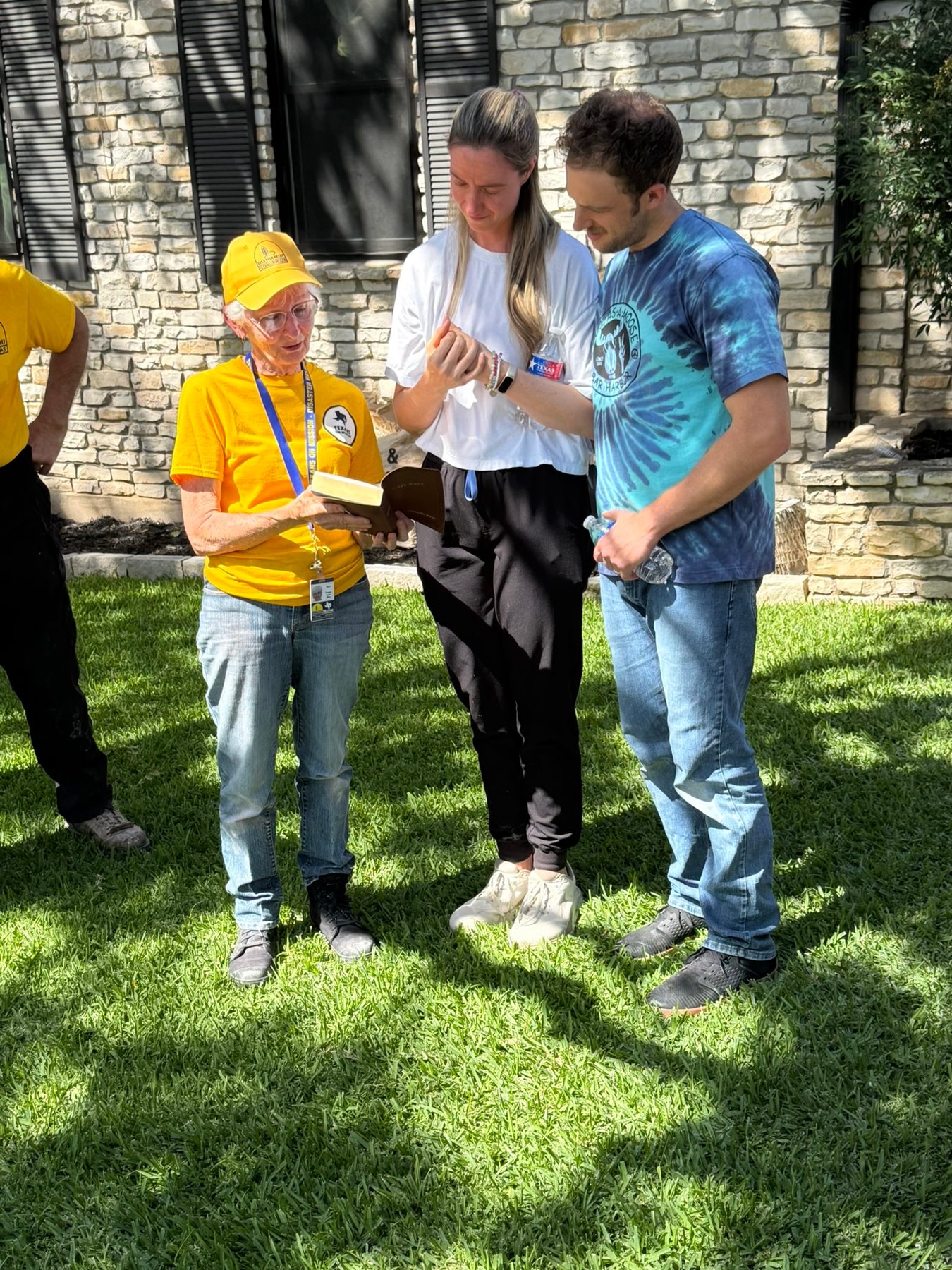 Texans On Mission volunteer shares a Bible and prays with two Kerrville residents.