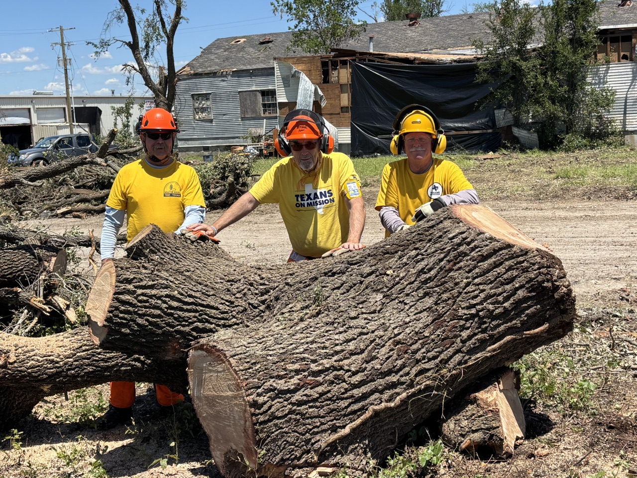 Texans On Mission equipment clearing debris beside a storm-damaged building in Mineral Wells.