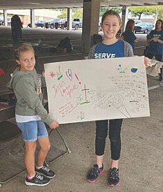 Children holding a Messages of Hope sign with handwritten encouragement.